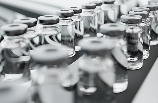 Vaccine vials on a production line in a pharmaceutical factory. Computer generated imagery of medicine for illness prevention.