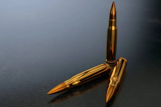 Photo of 3D golden bullets for a rifle on a dark surface in a dark space