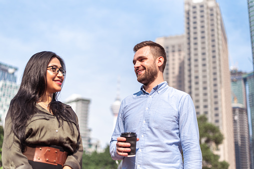 Smiling young couple having coffee break in city park