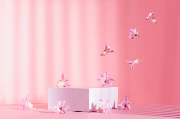 istock Romantic elegance three white square podiums with flow of levitate spring  flowers in sunlight with striped shadow on soft light pastel pink background. Fashion fresh showcase. 1316780484