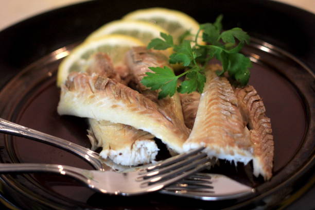 istock Cooked fish fillet on a dark plate, decorated with lemon .Whole fish cooked in a salt 1316782746