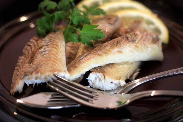 istock Cooked fish fillet on a dark plate, decorated with lemon .Whole fish cooked in a salt 1316782747