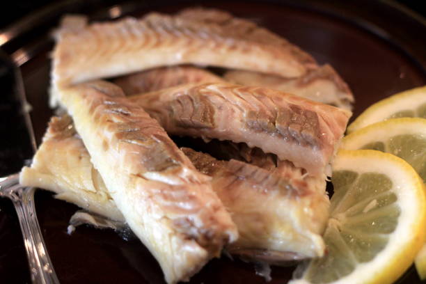 istock Cooked fish fillet on a dark plate, decorated with lemon .Whole fish cooked in a salt 1316782808