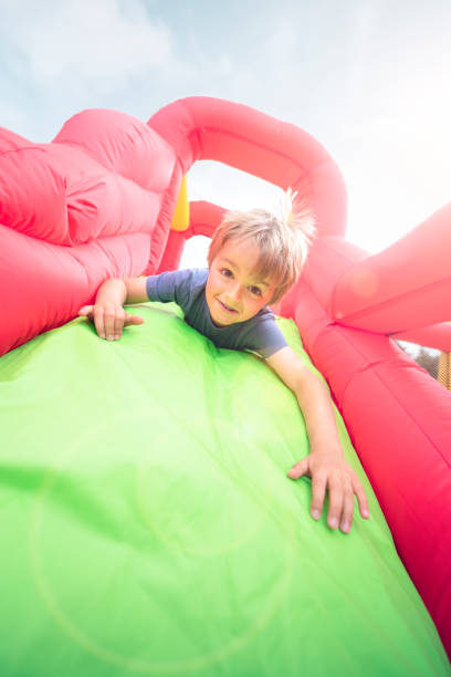 enfant sur la glissière gonflable de château gonflable - inflatable slide sliding child photos et images de collection