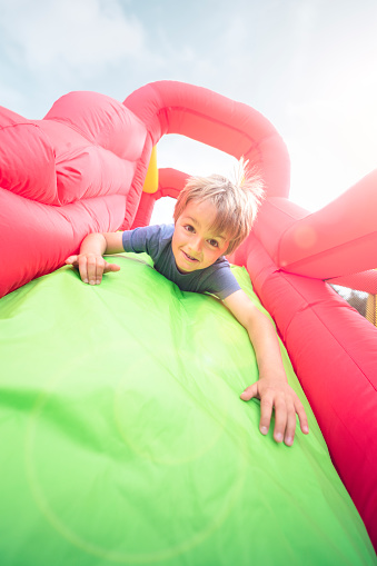 Boy jumping down the slide on an inflatable bouncy castle