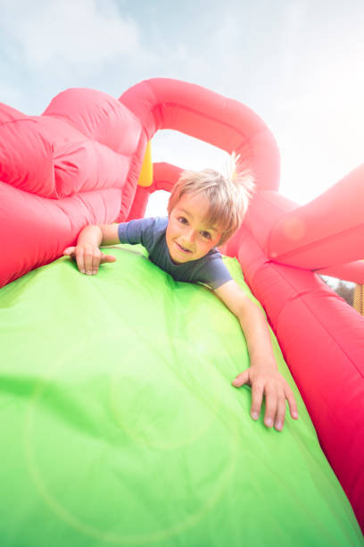 criança em escorregador inflável de castelo saltitante - inflatable slide sliding child - fotografias e filmes do acervo