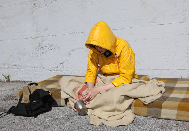 poor homeless young man begs for alms on a filthy mattress on the sidewalk