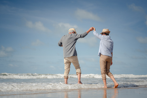 Senior couple dancing on the beach at sunny day. Plan life insurance with the concept of happy retirement.