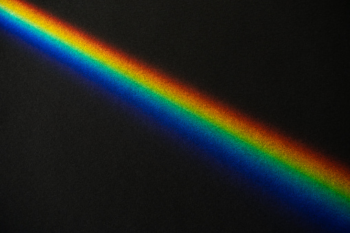 Rainbow prism streek on black textured paper background
