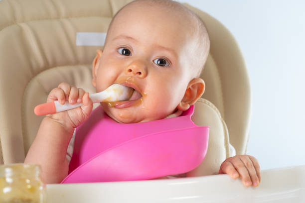 istock A newborn child with a spoon eats vegetable puree on his own. 1316790024