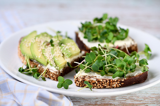 Sandwich rye bread with cereals, cream cheese, avocado and sprouted radish sprouts (microgreen)