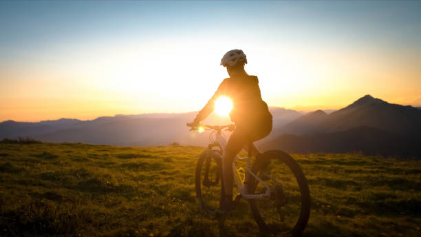 Girl teenager riding mountain bike into the sunset Girl teenager riding mountain bike into the sunset. Beautiful golden summer light. female mountain biker silhouette stock pictures, royalty-free photos & images