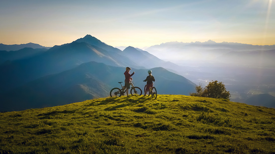 Two females on mountain bikes talking and looking at beautiful sunset