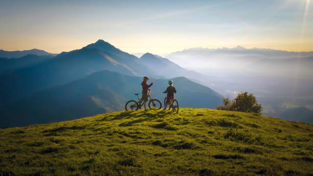 Two females on mountain bikes Two females on mountain bikes talking and looking at beautiful sunset balkans stock pictures, royalty-free photos & images