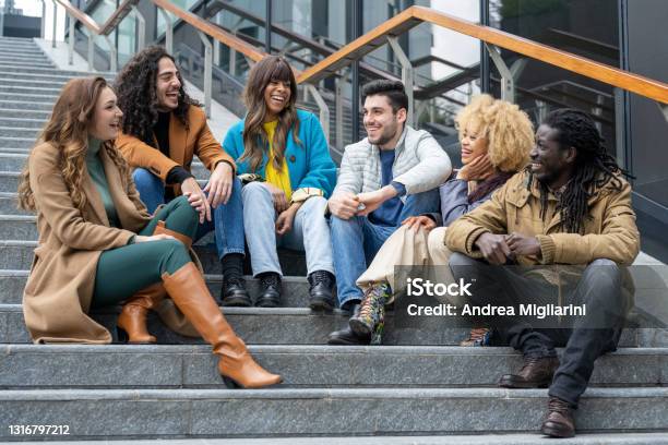 Group Of Smiling Young Adults On A Flight Of Steps Multiethnic Friends Having Fun And Laughing Resumption Of Sociality And Safety After The Pandemic Vaccinated People Gathering Stock Photo - Download Image Now