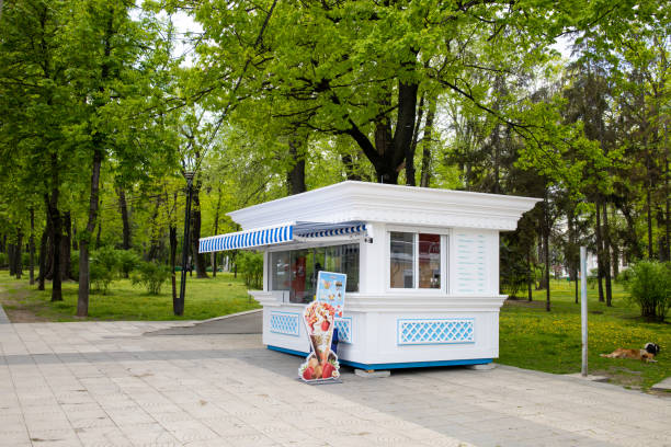 Beautiful modern white ice cream shop in the park with no people around it. Shop without costumers, exterior view. Chisinau, Republic of Moldova - May 2021