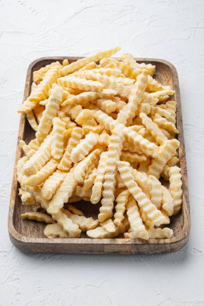 istock Frozen oven chips sliced potato, on wooden tray, on white background 1316799744