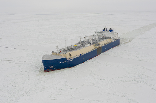 Sabetta, Yamal-Nenets Autonomous Area, Russia - April 7, 2021: VLADIMIR RUSANOV liquified petroleum gas tanker moves on ice. Overcast, light snow is falling.