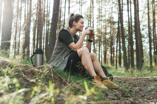 istock Hiker during small halt with a vacuum flask drinking hot coffee or tea in green forest 1316802877