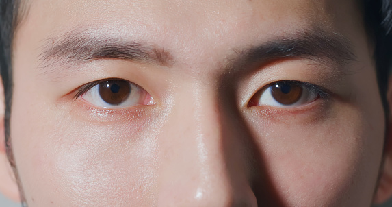 Close up of an African man's face. Eye macro with black iris. Close-up details and visible masculine features. Eyelashes and eyebrows in order.