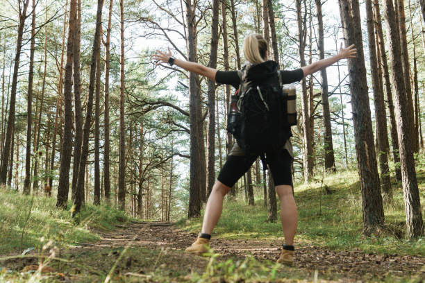 istock Female hiker with big backpack in green forest.  Focus on trees. 1316805387