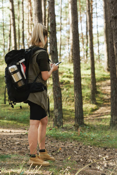 istock Female hiker is using smartphone for navigation in green forest 1316805634