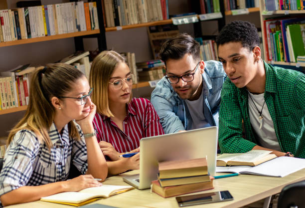 istock Four young students study in the school library, female student using laptop for researching online. 1316805857