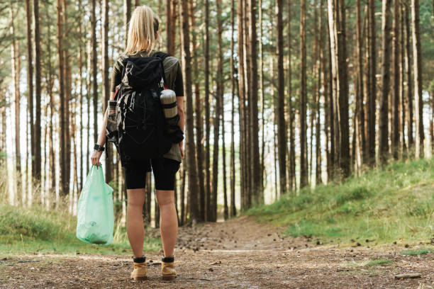 istock Female hiker collecting plastic waste in green forest 1316806610