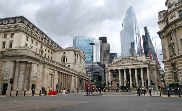 Bank of England, Threadneedle St and the Royal Exchange, London, United Kingdom Bank of England (left) off Threadneedle Street with red London double decker bus (ahead) and Royal Exchange (right) background of city skyscrapers. Outdoors on an overcast summers day.  May 4, 2021 bank of england stock pictures, royalty-free photos & images