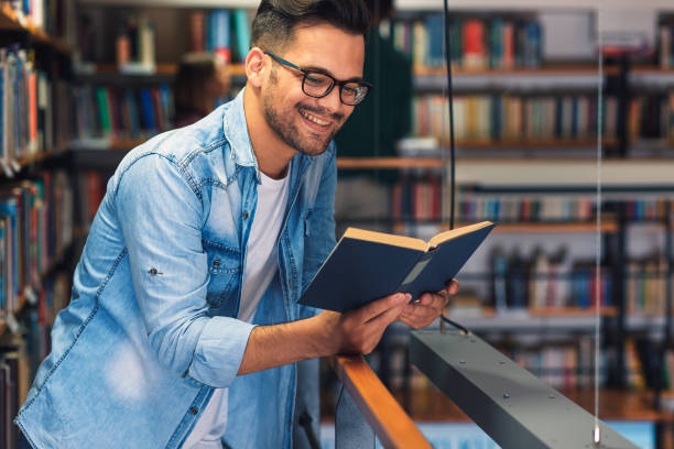 istock Young male student study in the library reading book near bookshelf. 1316807244