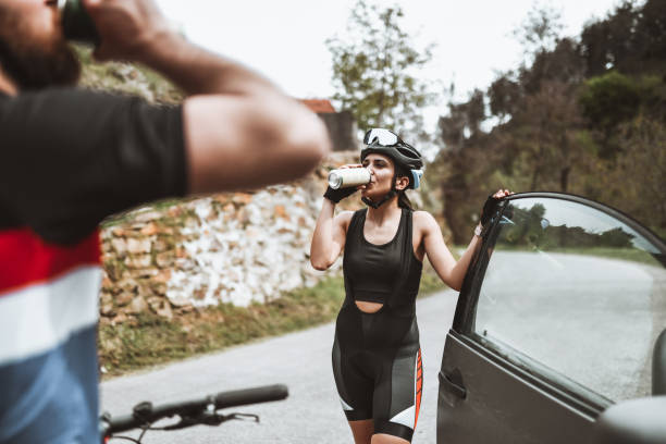 Male And Female Cyclists Drinking Water After Completing Planned Journey