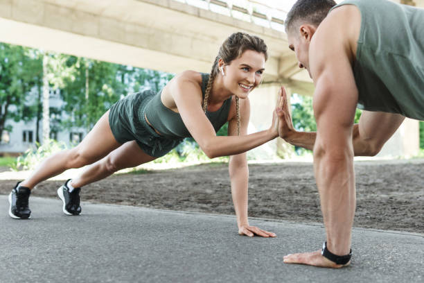 屋外でのアスレチックカップルとフィットネストレーニング。腕立て伏せ運動をしている男女。 - crossfit exercising sports training outdoors ストックフォトと画像