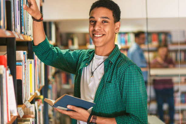 istock Young male student study in the library searching new book on bookshelf. 1316808717