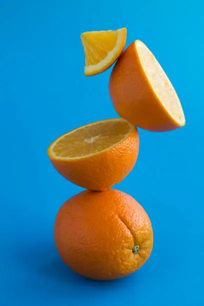 Orange-fruit stacked pyramid on the blue background.Close-up. Location vertical.