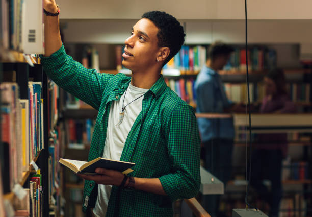 istock Young male student study in the library searching new book on bookshelf. 1316808969