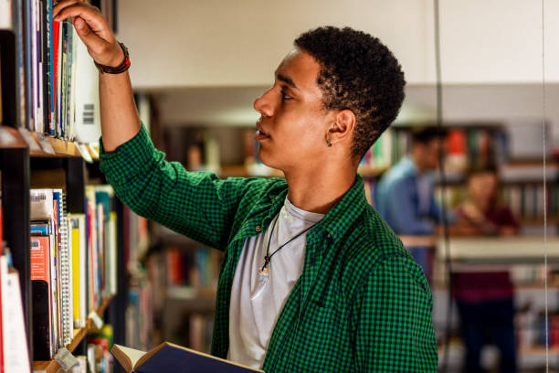 istock Young male student study in the library searching new book on bookshelf. 1316808971