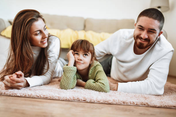istock Female Child Bored While Lying Down With Parents On Floor 1316815652