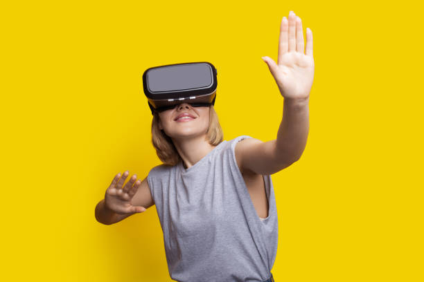 istock Caucasian blonde woman is touching something while experiencing new augmented reality headset on a yellow studio wall 1316820263