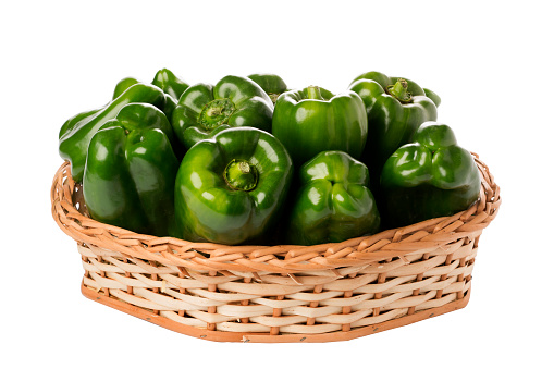 green peppers in wicker basket on isolated white background.