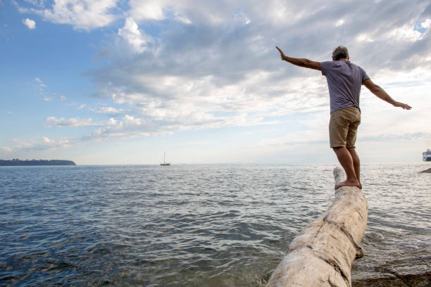 l’homme équilibre sur la notation au-dessus de la plage et de la mer méditerranée - shorts rear view summer beach photos et images de collection