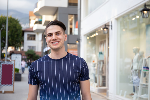 Portrait of young handsome man of Arabic ethnicity on the city streets. Iranian guy over with hipster hairstyle wearing casual attire. Close up, copy space for text.