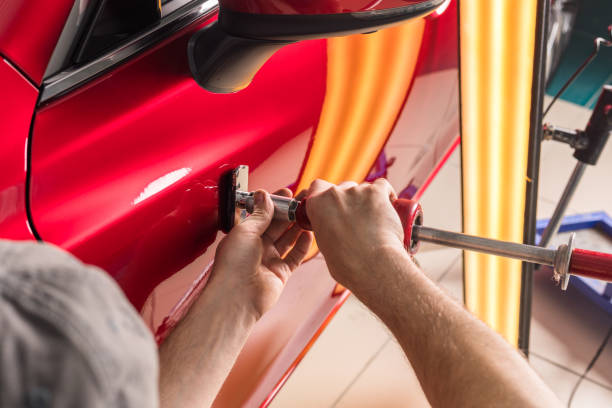 el técnico elimina las abolladuras en el coche utilizando el método sin pintar. pdr. reparación de carrocería de automóviles. - dented fotografías e imágenes de stock