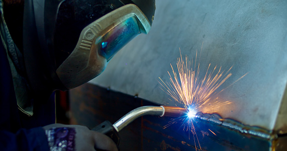 Close up of a helmeted metal worker welding.