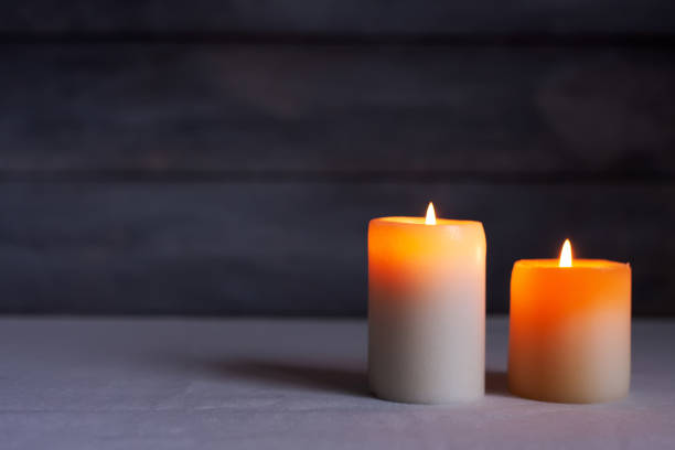 istock Close up of Two thick candles lit front view with rustic wood background 1316836407