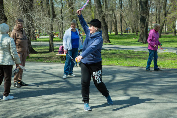 un grupo de personas de la tercera edad haciendo gimnasia de salud y fitness en el parque. los viejos hacen ejercicios de pelota de tenis y raqueta. - n64 fotografías e imágenes de stock