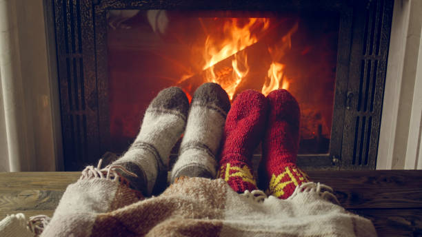 photo tonique des pieds de couple utilisant des chaussettes chaudes se trouvant sous la couverture par la cheminée brûlante - blanket fireplace winter women photos et images de collection