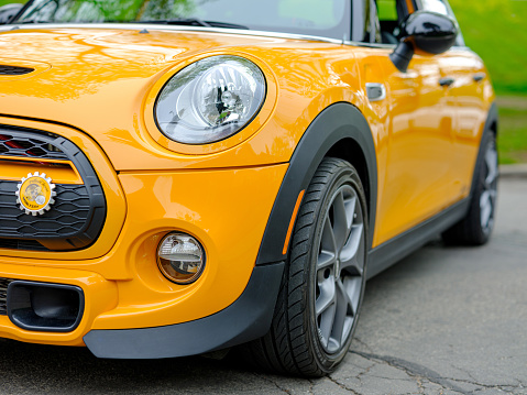 Toronto, Ontario, Canada- May 7, 20121. Part of the front end of Volcanic orange colour MINI COOPER parked on city street in East end of Toronto, Canada. Neighbourhood known as The Beaches, near Lake Ontario shore. MINI is slightly modified and has double bike racks on the roof.