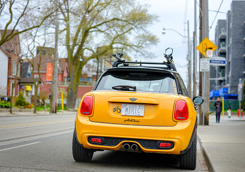 Toronto, Ontario, Canada- May 7, 20121. Rear view of Volcanic orange colour MINI COOPER parked on city street in East end of Toronto, Canada. Neighbourhood known as The Beaches, near Lake Ontario shore. MINI is slightly modified and has double bike racks on the roof.
