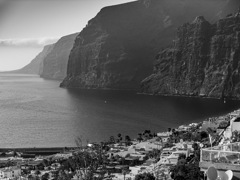Black and white photo of high cliffs on the ocean coast at Los Gigantes city, Tenerife island, Canaries