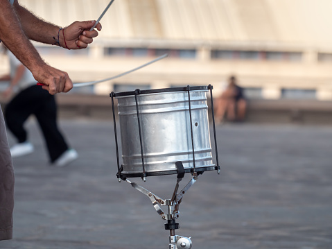 Closeup photo of male street musician plaing on drums with drum sticks